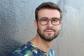 Young guy with a beard and mustache with glasses in a flowered or floral shirt posing on the street, fashion man, style, vintage Royalty Free Stock Photo