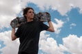 Young guy in a black t-shirt posing with his skateboard on his shoulders Royalty Free Stock Photo