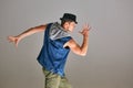 Young guy breakdancer in hat dancing expressive dance in studio isolated on gray background Royalty Free Stock Photo