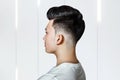 Young guy brunette with pompadour volume haircut 50s - 60s. real photo retro hair style for barbershop, side Royalty Free Stock Photo