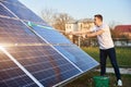 Young guy is cleaning solar panel on a plot near the house