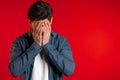 Young guy covers his face with hand from fatal disappointment, failure Royalty Free Stock Photo