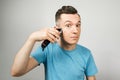 Young guy cuts himself with a clipper on a light background