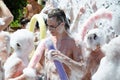 A young guy is dancing on the beach. Foamy party on the sandy beach