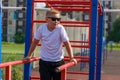 a young guy does push-ups on bars on a sports ground in the summer