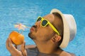 Young guy drinking fresh grapefruit juice in the swimming pool Royalty Free Stock Photo