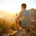 Young guy eating a protein bar at sunrise on a hike