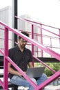 Young guy entrepreneur working outside using modern laptop sitting on stairs. Royalty Free Stock Photo