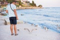 A young guy is feeding a flock of seagulls. Sun, summer, sea Royalty Free Stock Photo