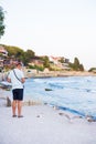 A young guy is feeding a flock of seagulls. Sun, summer, sea.