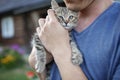 Young guy found and picked up little kitten during walking in field, homeless domestic animals care Royalty Free Stock Photo