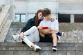 Young guy and a girl sitting on the street look into a red smartphone with a smile Royalty Free Stock Photo