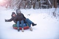 Young guy and a girl ski tubing in the winter ride down a hill