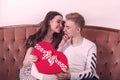 A young guy gives a gift to his beloved girl, a box in the form of a heart, a cute smile, a happy couple Royalty Free Stock Photo