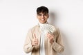 Young guy in glasses showing dollar bills and thumbs up, making money, standing with cash on white background Royalty Free Stock Photo