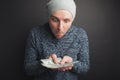 A young guy in a gray cap and a beard, holding a stack of money and stares at it on a black background. Freelancer admire its its Royalty Free Stock Photo