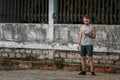 Young guy in a gray tank top and jeans shorts smokes