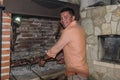 Young guy grills meat in a fireplace on an open fire