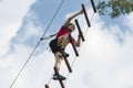 A young guy in a helmet climbs up a rope ladder against the blue sky. Mountaineering and climbing wall for tourists and vacationer Royalty Free Stock Photo