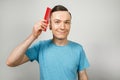 Young guy hold a comb and combs his hair and smiles on a white background. Close-up portrait Royalty Free Stock Photo