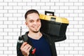 Young guy holding toolbox and screwdriver, Portrait of a handsome repairman with drill in the bright interior Royalty Free Stock Photo