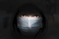 A young guy in a hooded sweatshirt in a medical mask on a dark background.Personal safety of young people in Europe.