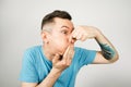 Young guy inserts two fingers in the mouth to induce vomiting, on a light background