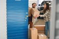 Young guy and lady with big cardboard boxes in self-storage unit Royalty Free Stock Photo