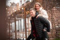 Young guy laughs and carries a beautiful girl on his back. Yellow bokeh in the background. Valentine`s day concept Royalty Free Stock Photo