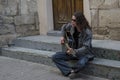 Young guy with long hair in sunglesses playing guitar on the street Royalty Free Stock Photo