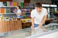 Young guy looks and chooses frozen food in refrigerator in supermarket Royalty Free Stock Photo