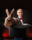 A young guy magician illusionist holding a hat with a rabbit