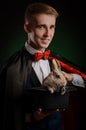 A young guy magician illusionist holding a hat with a rabbit