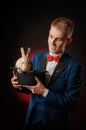 A young guy magician illusionist holding a hat with a rabbit