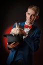 A young guy magician illusionist holding a hat with a rabbit