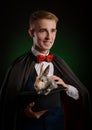 A young guy magician illusionist holding a hat with a rabbit