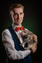 a young guy magician illusionist holding a hat with a rabbit