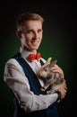 a young guy magician illusionist holding a hat with a rabbit