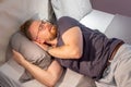 Young guy man beard fell asleep in glasses on a bed in clothes in the bedroom with the lights on. Fatigue, lack of sleep, stress, Royalty Free Stock Photo