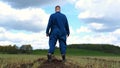 A young guy man, a farmer in a working uniform, walks across a field in rubber boots. Concept of: Freedom, Rubber boots, Lifesty Royalty Free Stock Photo