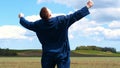 A young guy man, a farmer in a working uniform, walks across a field in rubber boots. Concept of: Freedom, Rubber boots, Lifesty Royalty Free Stock Photo