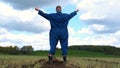 A young guy man, a farmer in a working uniform, walks across a field in rubber boots. Concept of: Freedom, Rubber boots, Lifesty Royalty Free Stock Photo