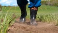 A young guy man, a farmer in a working uniform, walks across a field in rubber boots. Concept of: Freedom, Rubber boots, Lifesty