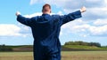 A young guy man, a farmer in a working uniform, walks across a field in rubber boots. Concept of: Freedom, Rubber boots, Lifesty Royalty Free Stock Photo