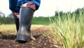 A young guy man, a farmer in a working uniform, walks across a field in rubber boots. Concept of: Freedom, Rubber boots, Lifesty Royalty Free Stock Photo