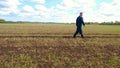 A young guy man, a farmer in a working uniform, walks across a field in rubber boots. Concept of: Freedom, Rubber boots, Lifesty Royalty Free Stock Photo