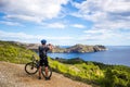 A young guy on a mountain bike trails in Spain and takes a photo on a white phone in the background of the Mediterranean Royalty Free Stock Photo