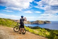 A young guy on a mountain bike trails in Spain and takes a photo on a white phone in the background of the Mediterranean sea of Royalty Free Stock Photo