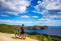 A young guy on a mountain bike trails in Spain and takes a photo on a white phone in the background of the Mediterranean Royalty Free Stock Photo