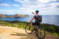 A young guy on a mountain bike trails in Spain and takes a photo on a white phone in the background of the Mediterranean Royalty Free Stock Photo